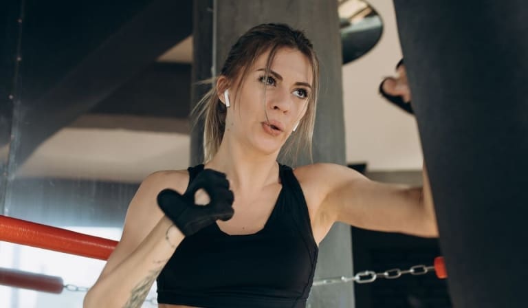 Female Punching a Boxing bag With Boxing Gloves at the gym