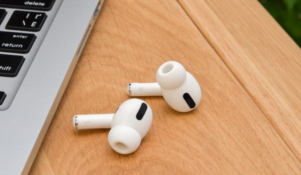 Wireless white headphones `airpods` near the laptop 