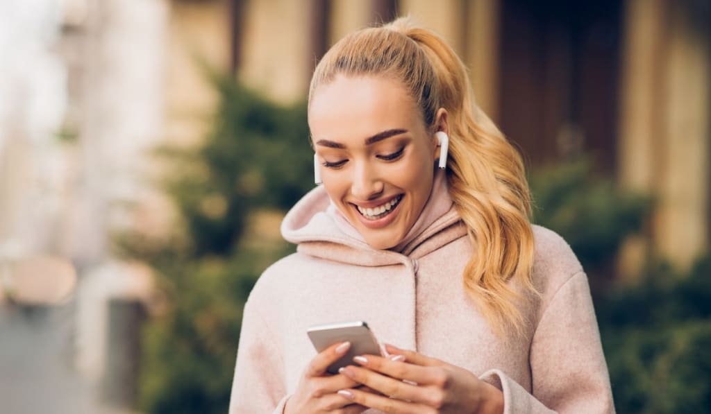 Woman messaging on phone outdoors on city street 