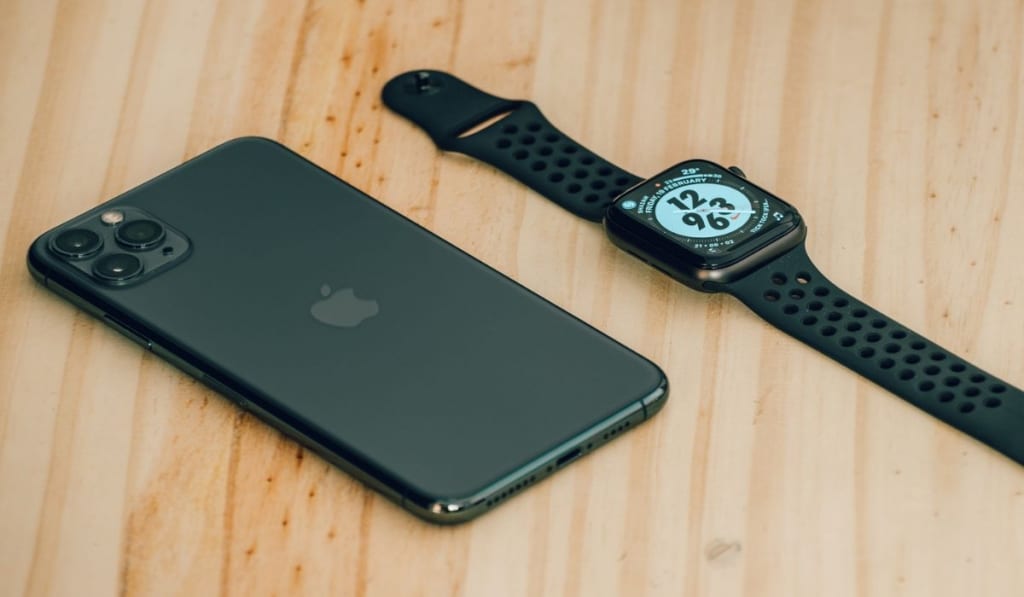Apple iPhone 11 pro max and apple watch series 6 lay flat on a wooden table 