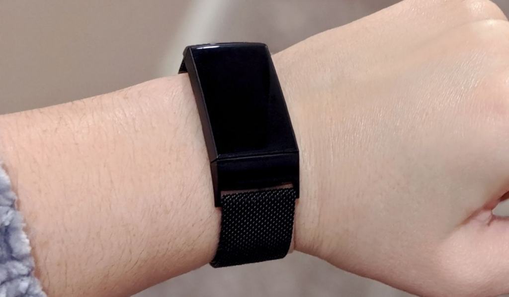 Black fitness tracker with metal band on a wrist 