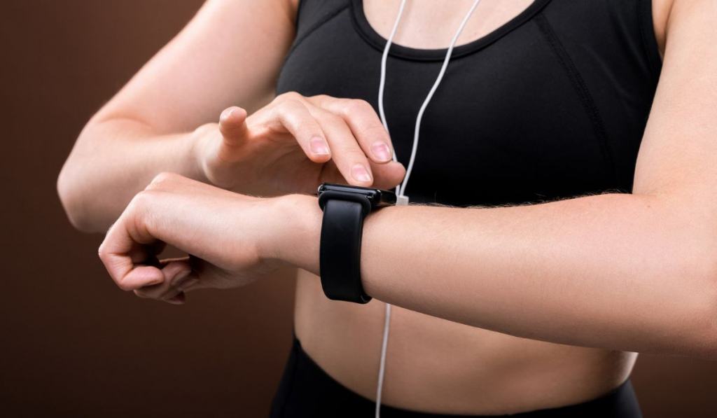 Mid section of young sportswoman in activewear switching on her fitbit on wrist 