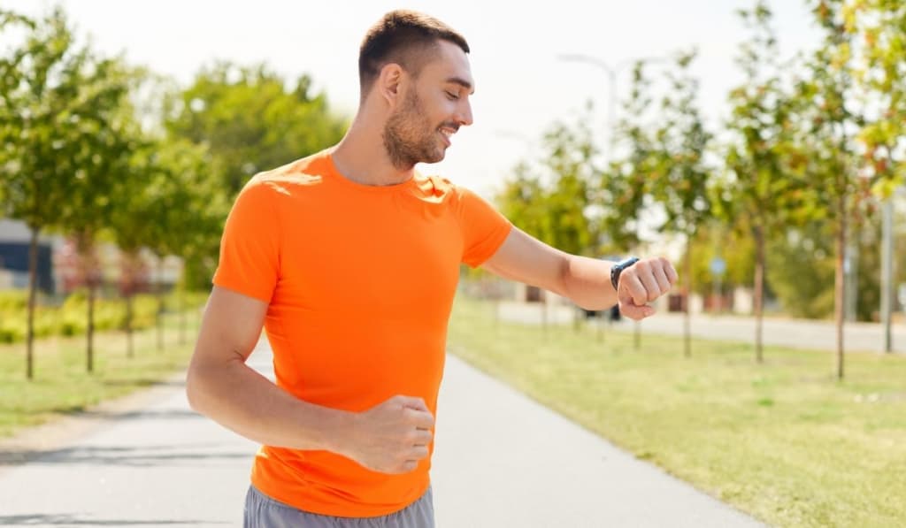 Smiling man with smart watch running outdoors 