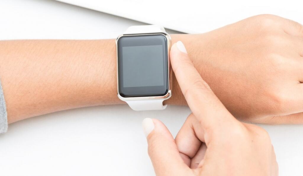 Woman touching smart watch hand on work table