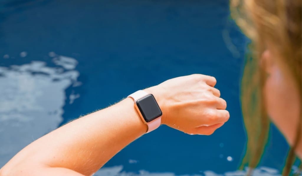 Young woman wearing digital watch on hand by the pool 