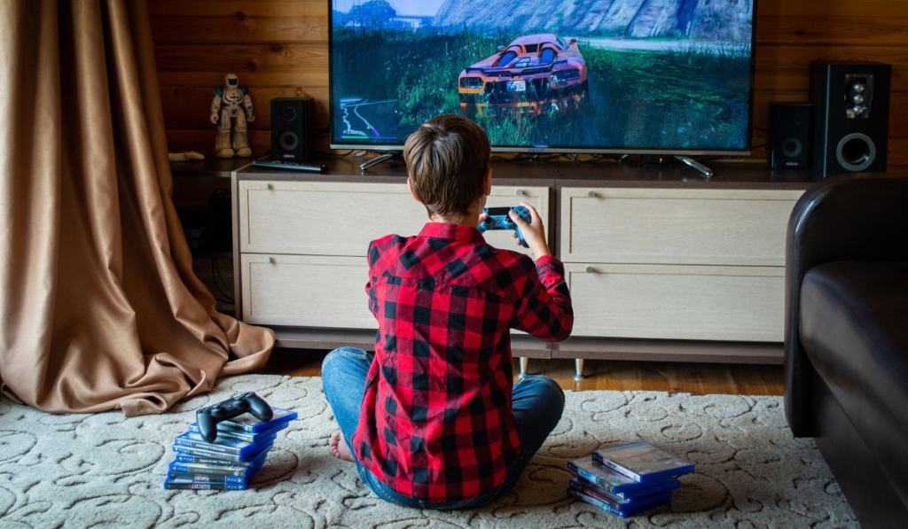 Back View of a Boy in Red Plaid Shirt Playing a Video Game