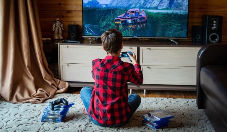 Back View of a Boy in Red Plaid Shirt Playing a Video Game