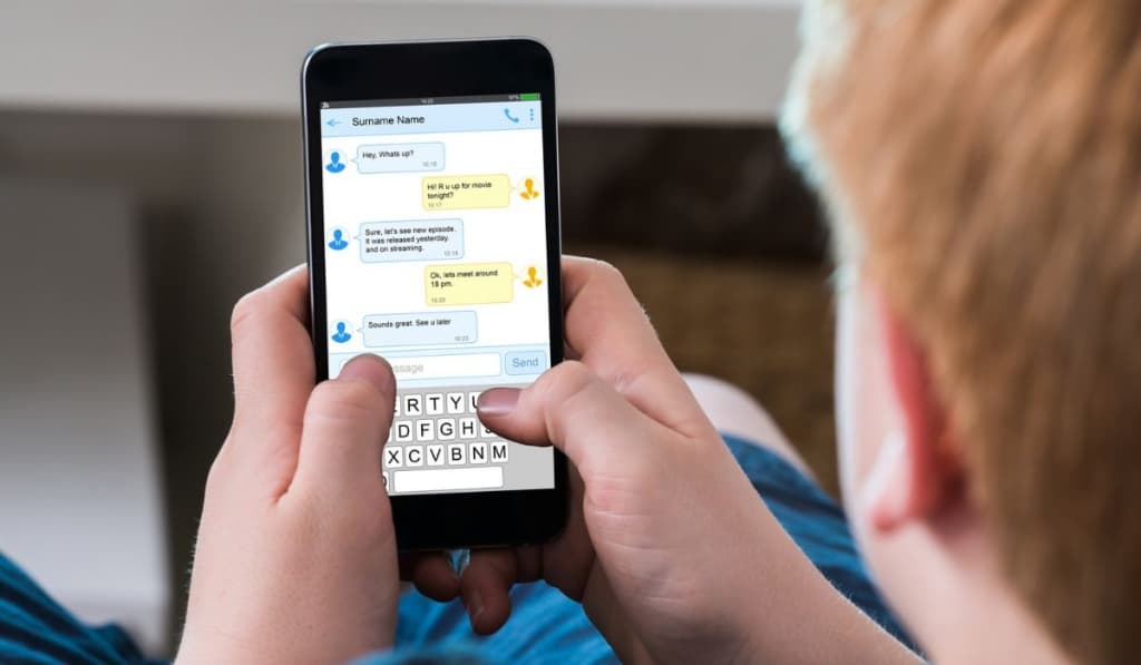 Boy Typing Text Message On Mobile Phone