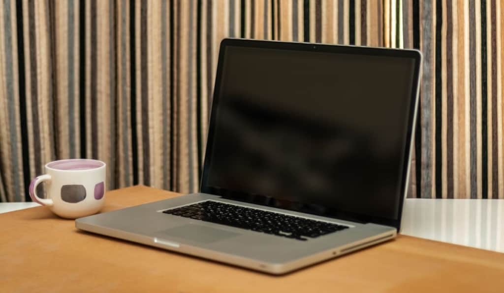 Laptop Computer With Black Screen On The Table In Office Along With A Coffee Cup