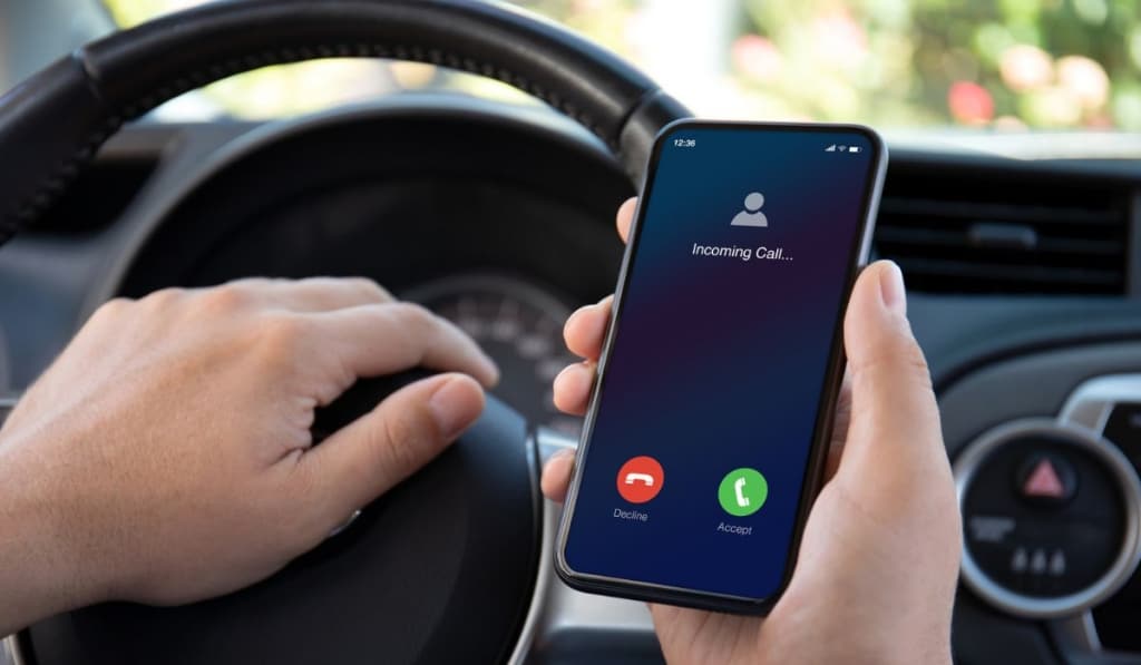 Male hands driving car holding phone with incoming call screen 