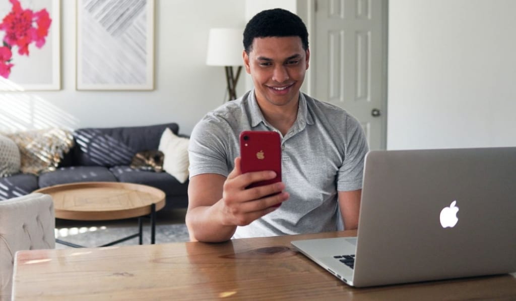 Man holding his phone in front of his computer