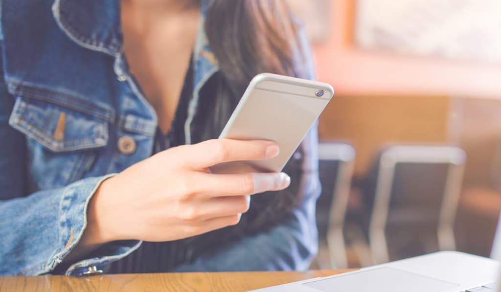 Woman sitting at a desk using a smartphone