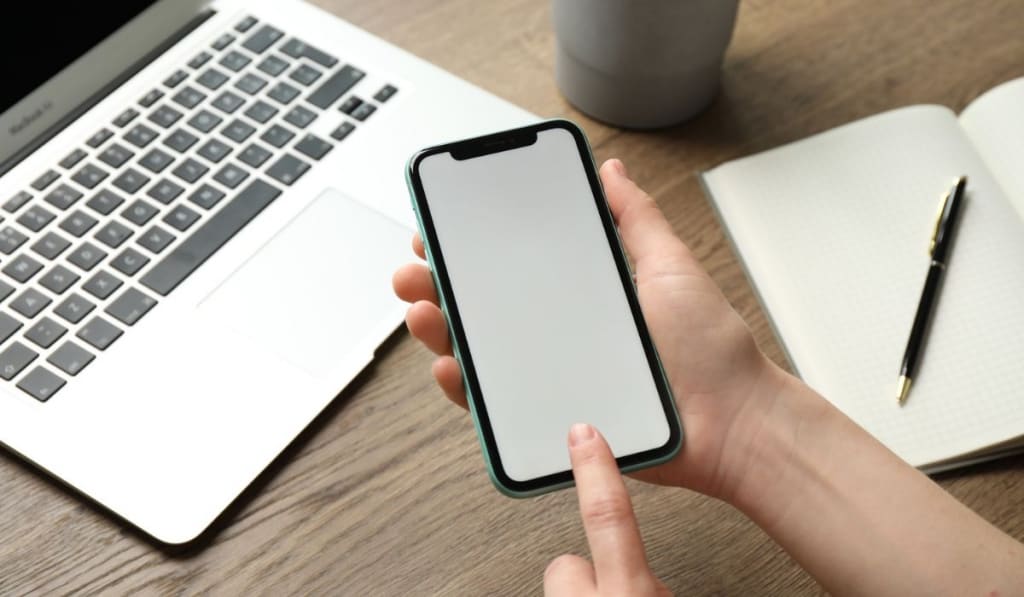 Woman using Iphone 11 Pro Max with blank screen at workplace