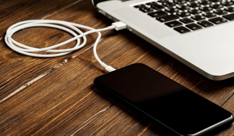 A USB cable connects your phone and laptop