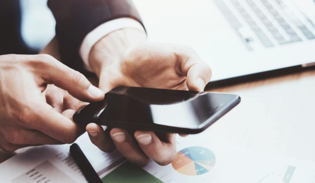 Closeup view of male hands holding modern mobile phone with and pointing finger to home button