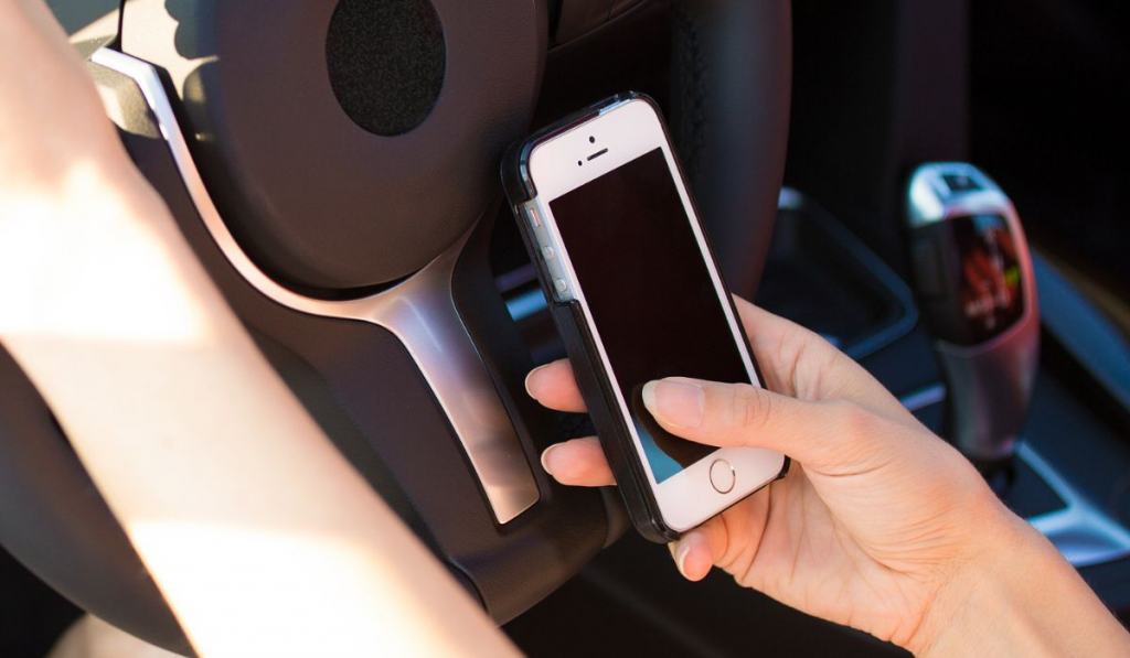 Woman sending text message on smart phone while driving to work