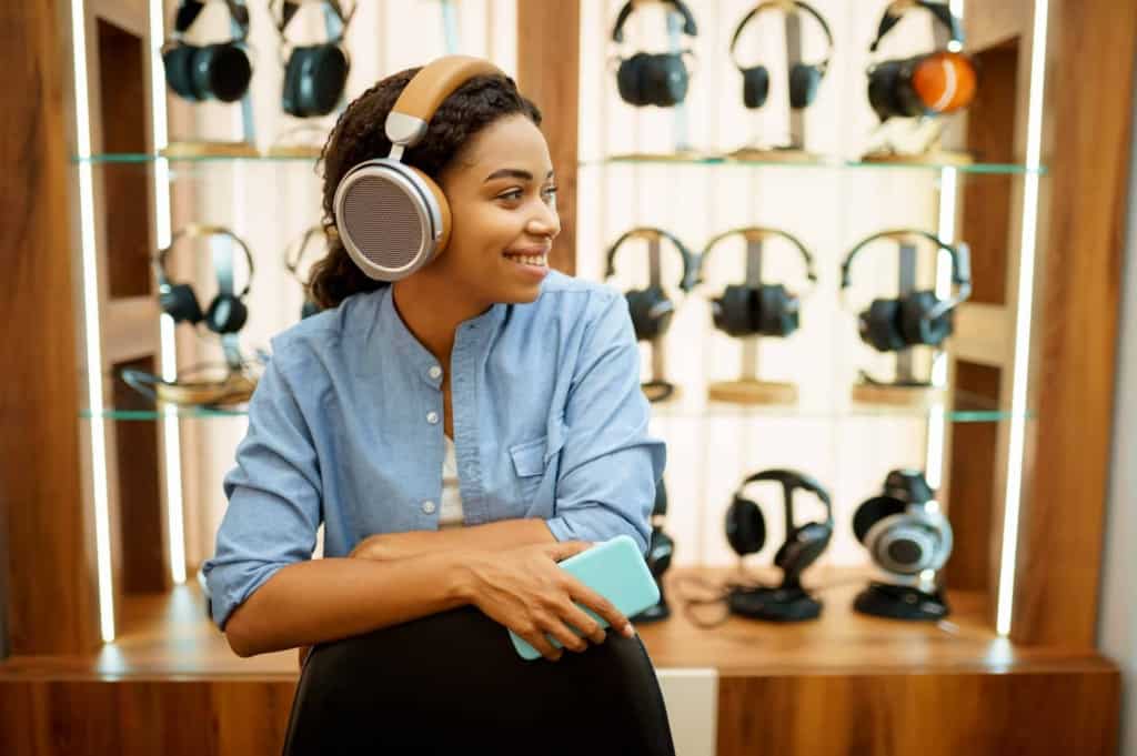young woman listening to music headphones store 1 Is Bluetooth Audio Better Than Optical?