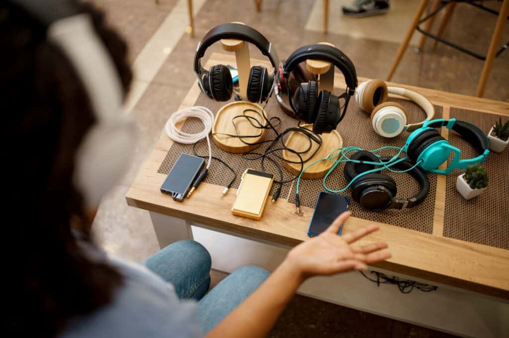 woman choosing headphones in speaker systems store 1024x681 1 Which Headphones Can Connect to 2 Devices
